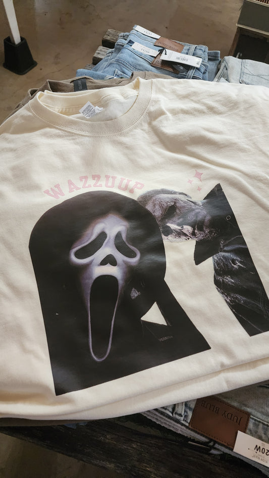 A cream-colored t-shirt featuring a large graphic print of the Ghostface mask from the Scream franchise, with a smaller Ghostface figure above it and pink text reading 'SLEEPER' on the left side.